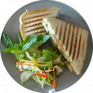 'Caprese-Sandwich' mit Tomate, Mozzarella, Pesto, Rucola und frischen Basilikum (2,19,81) dazu als Menüoption Pommes und House-Dip (9,22)