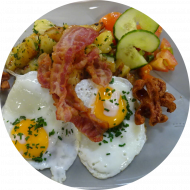 Frühstück in der Cafeteria StraNa: 'SchMACofatz - knusprige Bratkartoffeln mit Bacon, Grillwürstchen und 2 Spiegeleiern (1,2,3,15,51), dazu ein Heißgetränk 0,2l 