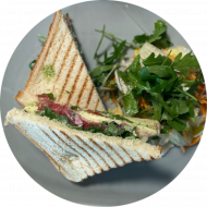 Rucola-Serrano-Sandwich mit Oliven, Mozzarella, Tomaten und Balsamico Glace (1,2,3,6,19,81) dazu Menüoption verschiedene Pommes und House-Dip (9,22)