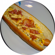 'Cheesy Bacon Dog' XXl Hot Dog mit Bacon und Cheddar und Gewürzgurken dazu Kartoffelspalten (1,2,3,9,19,21,51,52,81,83) 