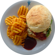 Chicken Burger mit Currymayo, Eisberg, Tomate, Gurke und roten Zwiebeln (22,23,54,81) dazu Gitterkartoffeln (81)