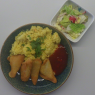 'Samosas' gefüllte Teigtaschen (21,22,49,81) mit scharfer Chilisoße (9,18,49,81) auf Pfannencouscous mit frischem Koriander (21,49,81) und Salatgarnitur