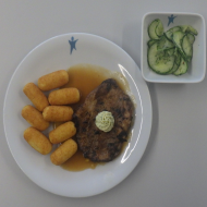 Schweinenackensteak in Basilikum-Bärlauch-Marinade mit Kräuterbutterrossette (1,2,18,19,22,81) an Bratensoße (81) dazu Kroketten (81) und kleiner Gurkensalat mit Dill